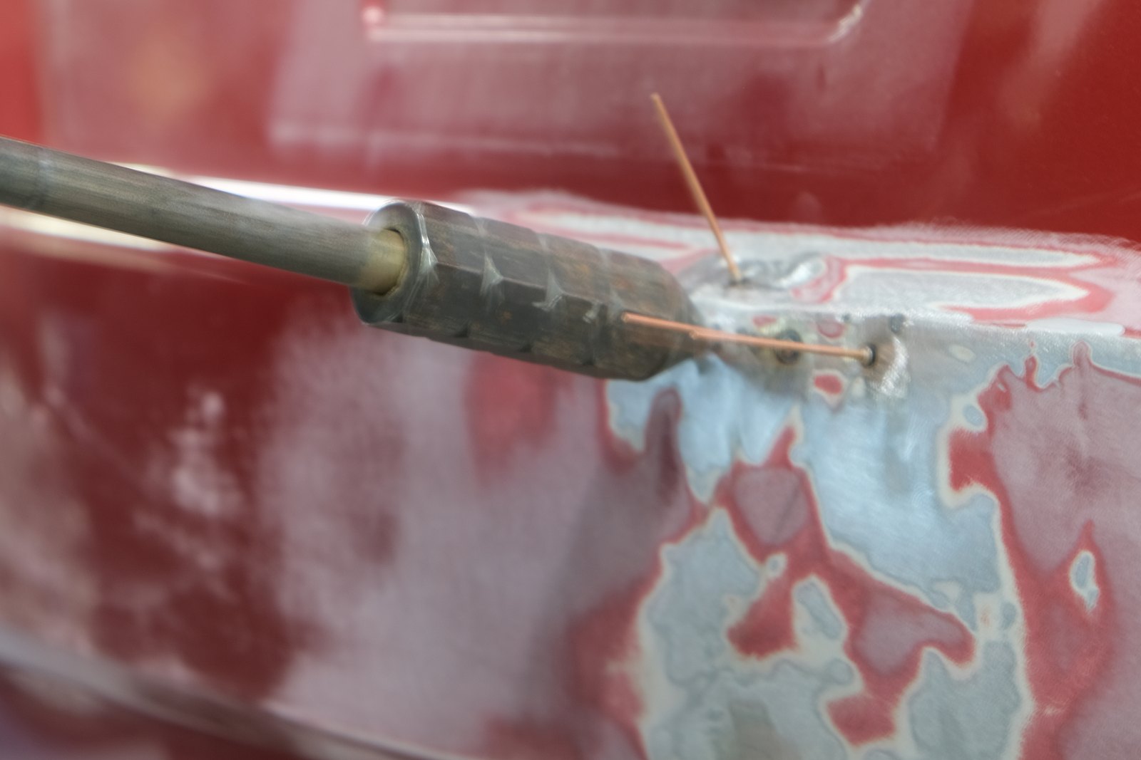 Tige de traction utilisée sur un panneau rouge poncé, pour ramener le métal à sa forme